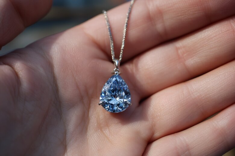 Un'immagine delicata e rispettosa di mani che reggono un ciondolo con diamante blu commemorativo